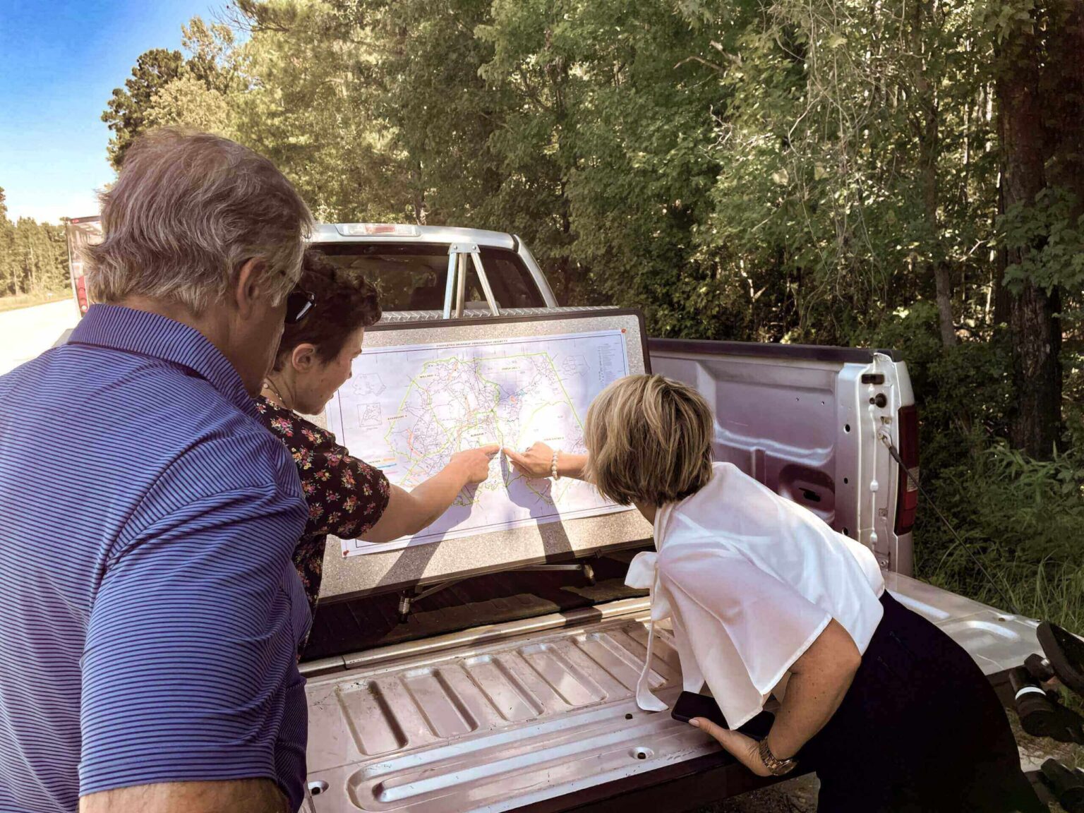 people point to map on bed of pickup truck